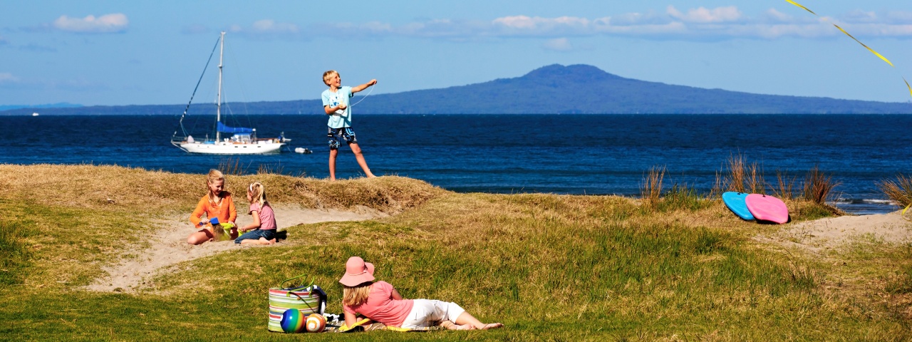 Family enjoying summer weather with Rangitoto Island in the background